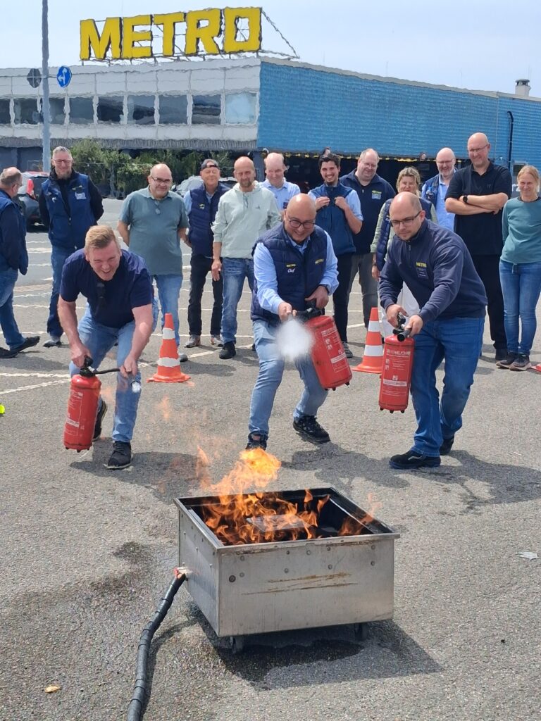 Teilnehmer einer Brandschutzhelfer-Schulung bei einer praktischen Feuerlöschübung mit Feuerlöschern